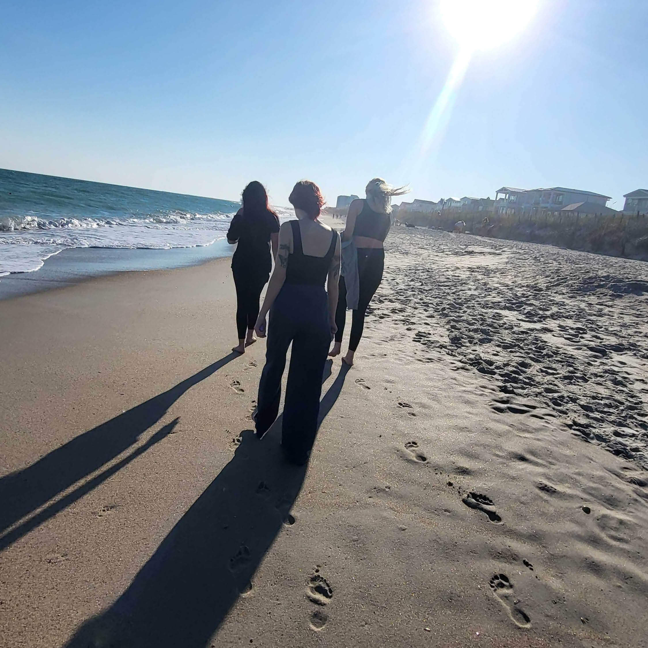 three young women walking on the beach