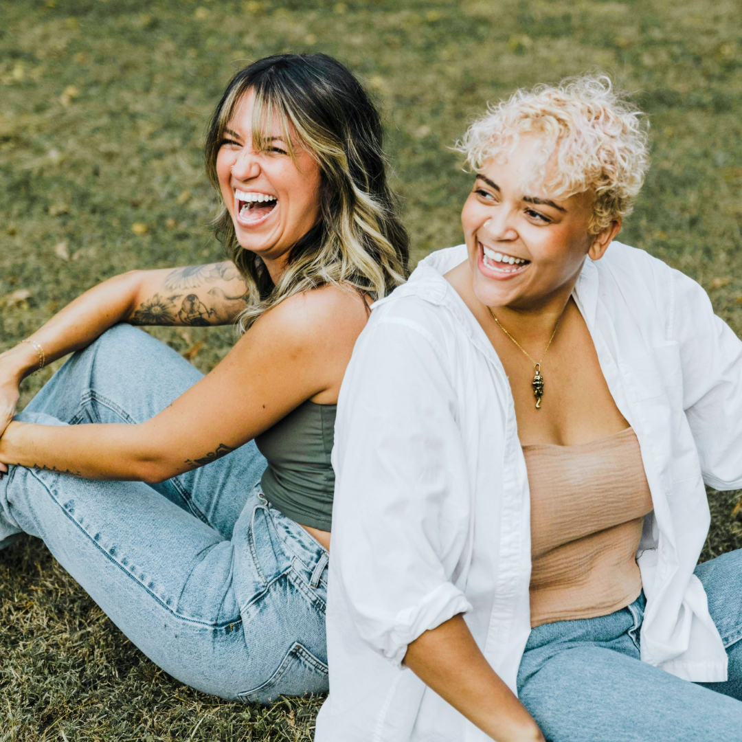 two women sitting on the ground laughing