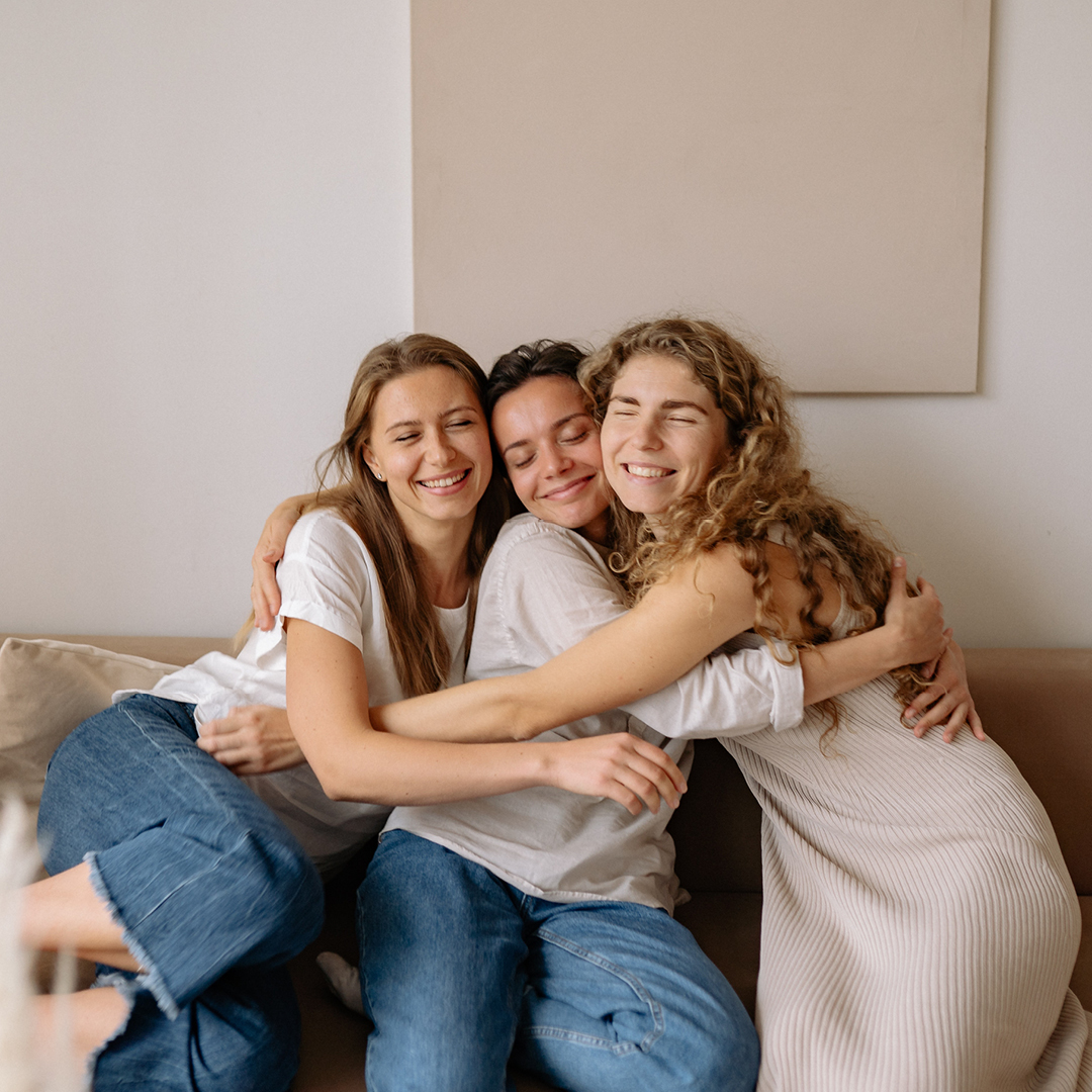 three women hugging on a couch